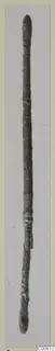 Long slender bronze rod with rounded ends, photographed upright; find from Vouni tomb T. 1-16