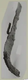 Corroded, curved iron tool from Vouni, with a short iron rod lying against its upper edge.
