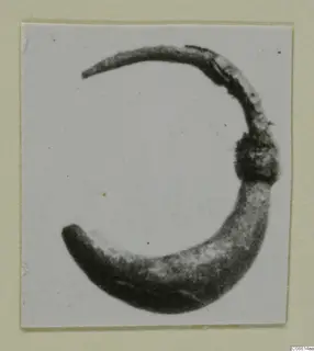 Curved fragment of a dark object from Vouni, shown as a photograph mounted on a cream card.