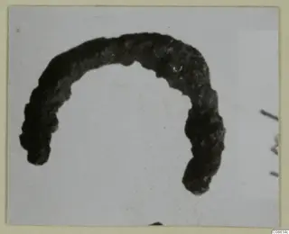 Corroded bronze finger ring from Vouni, shown as an open curved arc against a pale background.