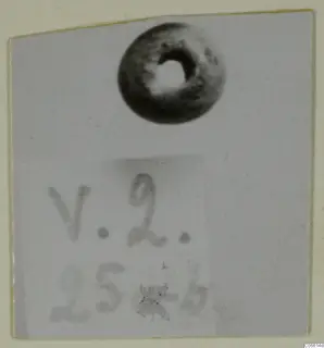 Small dark ring-shaped bead with a round central hole, Vouni, shown above a handwritten label