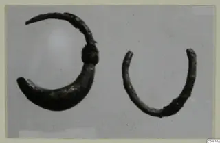Two corroded silver hoops, one larger than the other, photographed on a plain grey background
