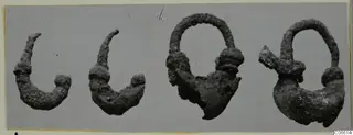 Four corroded silver objects, two curved hook-like pieces and two loop-shaped pieces, shown side by side on a grey background