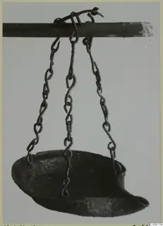 Metal lamp hanging by three chains from a horizontal rod