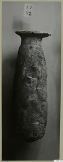 Alabaster vase with a flaring rim and long, rounded body, photographed against a grey backdrop.