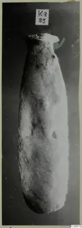Tall pale stone vessel with a narrow flared neck, photographed against a dark background, from Vouni