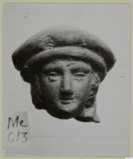 Terracotta head with a rounded cap-like headdress, shown from the front against a pale background
