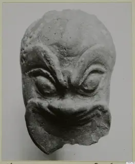 Small terracotta head from Mersinaki with heavy brow ridges, bulging eyes and a wide grimacing mouth