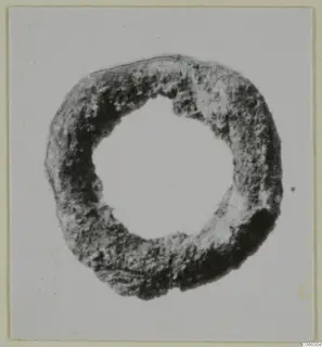 Ring-shaped bronze fragment from Mersinaki, seen face-on against a pale card background.