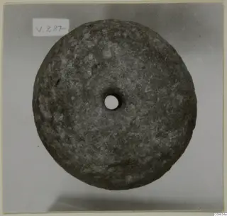 Stone loom weight from Vouni, a flat round disc with a central hole