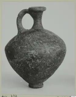 One-handled dark pottery jug with a narrow neck, flared rim and dotted decoration on the body.