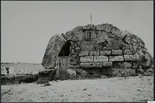 Built tomb with a tomb chamber, its arched entrance closed by a wooden door with a cross on it.