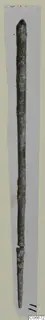 Long, thin bronze object with a pointed top, shown vertically on a light grey background