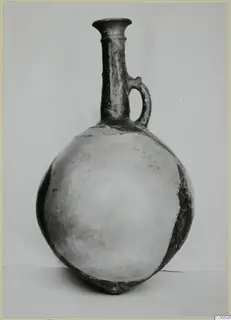 Pottery jug with a tall flared neck and single loop handle, photographed against a plain backdrop