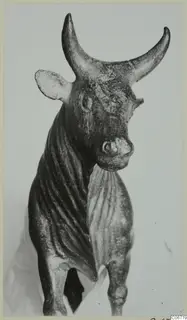 Bronze figurine of a standing bull with upswept horns, pointed ears and a ribbed neck and flank.