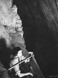 Joan du Plat Taylor measuring with an instrument on a tripod inside the cave at Fylleri, Kythrea.