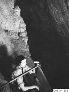 Joan du Plat Taylor measuring with a tripod-mounted instrument on a ledge inside the cave at Fylleri, Kythrea.