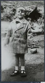 Stefan Gjerstad as a small child in a belted tweed coat, standing on bare ground in Nicosia