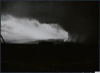 Storm clouds over distant hills, with a bright cloud bank to the left and a dark sky above