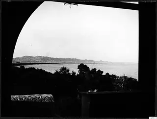 View through an arched opening over trees and calm water toward a distant mountain range near Famagusta