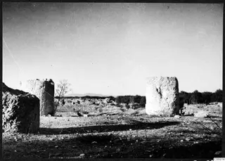 Large weathered stone column drums standing among ruins at Salamis, with low hills in the distance.