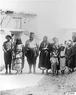 The priest and his family standing in a dirt street in front of a whitewashed building at Mandres.