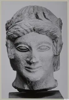 Limestone head of a figure from Mersinaki, shown on a dark stand