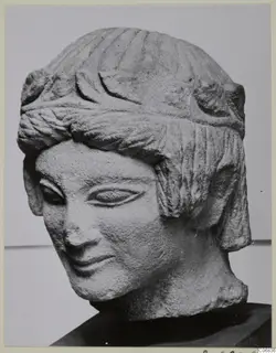 Carved limestone head of a figure with ridged hair, a band across the forehead, and a slight smile, from Mersinaki
