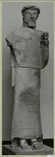 Terracotta statue of a standing bearded man in a long garment, reassembled from broken pieces