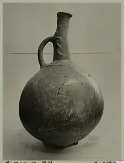 Pottery Red Polished I jug from Lapithos, with a long neck, single loop handle and repaired cracks on the body