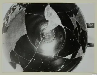 Interior of a black-glazed bowl reassembled from sherds, with a patterned medallion at the centre