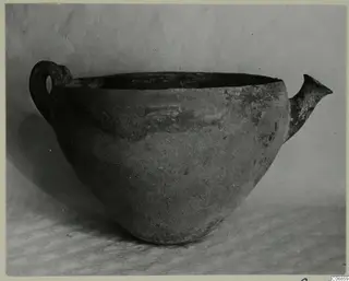 Red Polished III bowl with a loop handle and a spout-like lip, photographed on a draped cloth