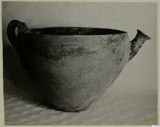 Red Polished III bowl with a loop handle and a spout-like projection, photographed on a patterned cloth.