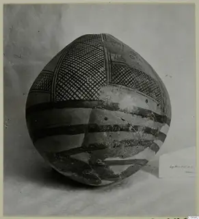 Round-bodied painted pottery vessel with cross-hatched panels and dark bands, photographed on a cloth backdrop.