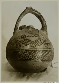 Painted pottery jug with a tall strap handle and dark geometric bands on a pale body