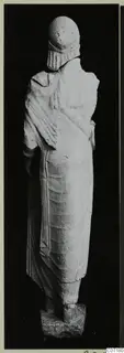 Back view of a standing limestone statue from Vouni, wearing a cylindrical headdress and long draped garment.