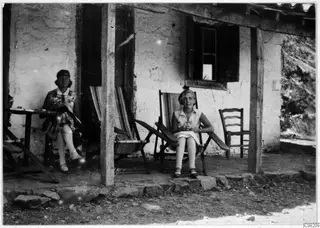 Vivi Gjerstad and Gudrun Atterman seated on a verandah in front of a whitewashed building at Machairas