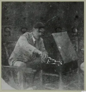 Man seated beside a dark box-like object with metal fittings at Machairas, possibly Einar Gjerstad