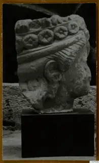 Carved stone architectural fragment with a row of round discs with star-like centres, on a dark stand