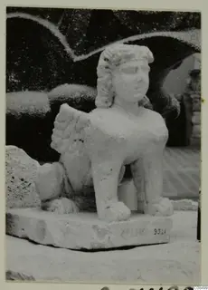 Pale stone statue of a seated winged figure with a human-looking head, on a rectangular base, from Soli
