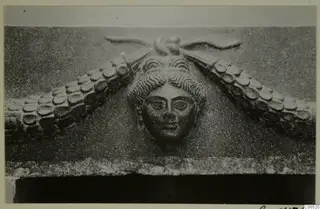 Carved stone relief of a woman's face framed by scalloped forms, find from North Africa