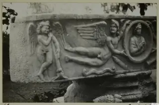 Carved stone block with relief figures of winged figures and an oval medallion bust, outdoors, Carthage.