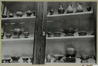 Pottery vessels and bowls on shelves inside a glass-fronted display cabinet