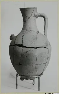 Pottery White Painted VI jug with a loop handle and small spout, standing on a wire stand