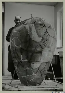 Large reconstructed pottery pithos with raised ridged bands, with a man in a dark coat standing behind it