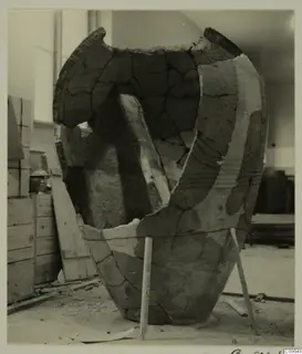 Large pottery pithos, broken and mended, propped with wooden sticks in a storeroom