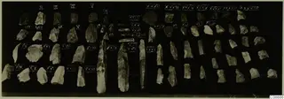 Rows of chipped stone blades and flakes on a dark background, each beside a white numeral label.
