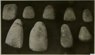 Nine smooth stone objects, rounded and tapering, arranged in two rows on a dark background