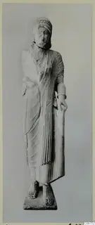 Limestone statue of a standing woman from Vouni, holding a tall rod, on a rectangular base