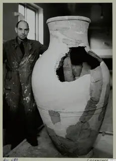 Large reconstructed pottery jar with a man in a paint-spattered coat standing beside it